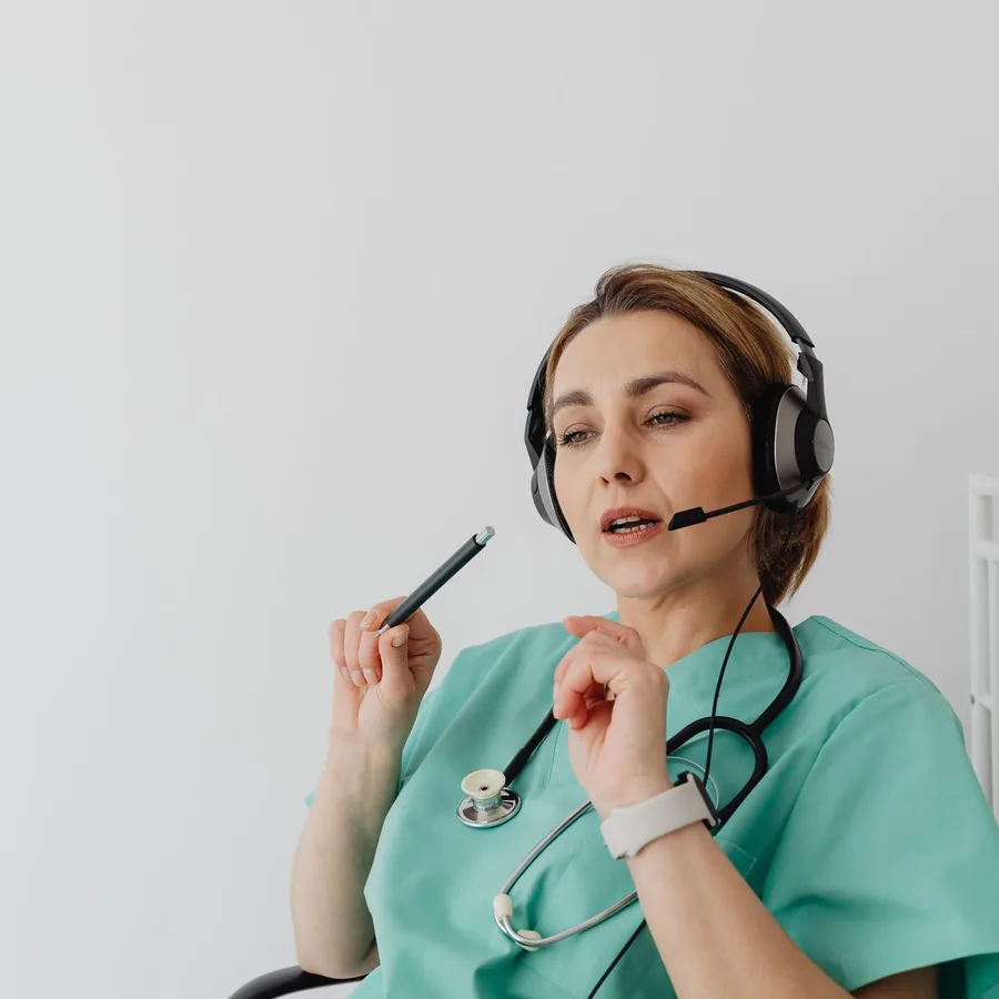 A nurse wearing a phone headset, listening and taking notes during a call